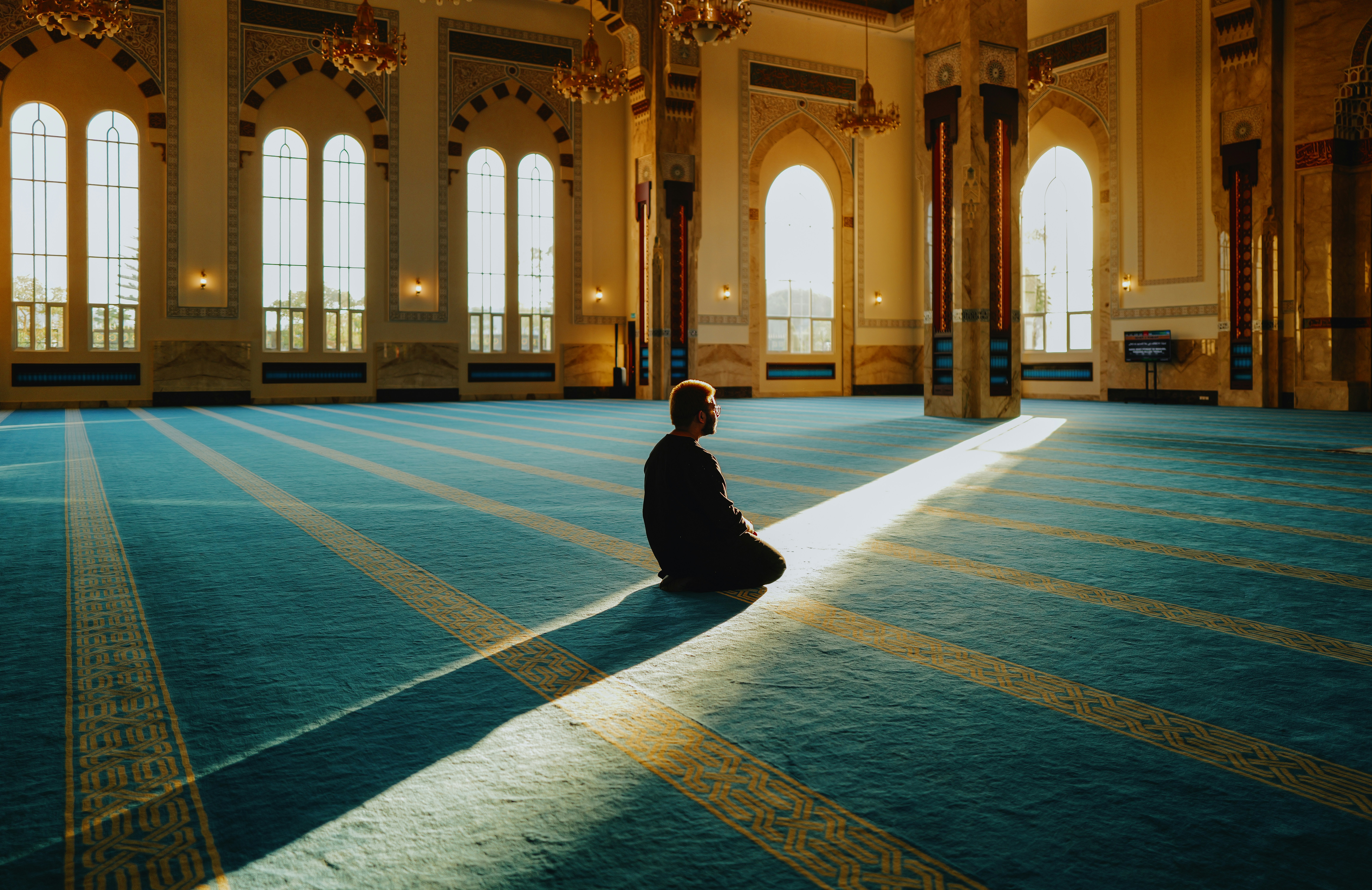 Voyage muslim avec un homme priant dans une grande mosquée lumineuse pendant un séjour spirituel et culturel musulman